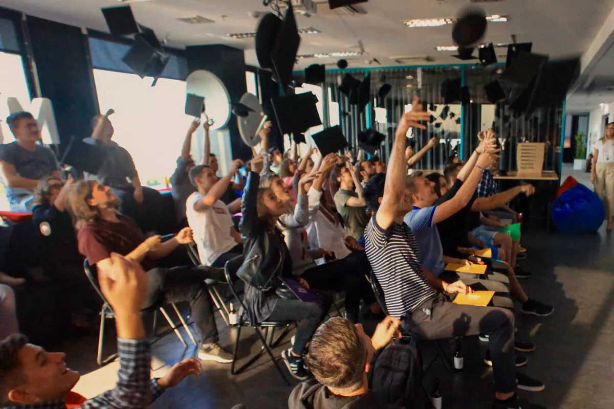 Students joyfully throw graduation caps in the air, celebrating the completion of a program.